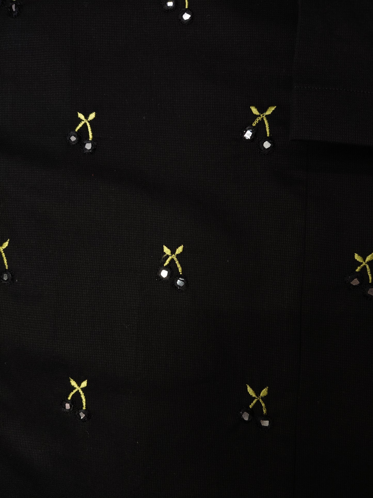 Close-up of the embroidery detail of the shirt featuring hand-done mirror work to resemble cherries