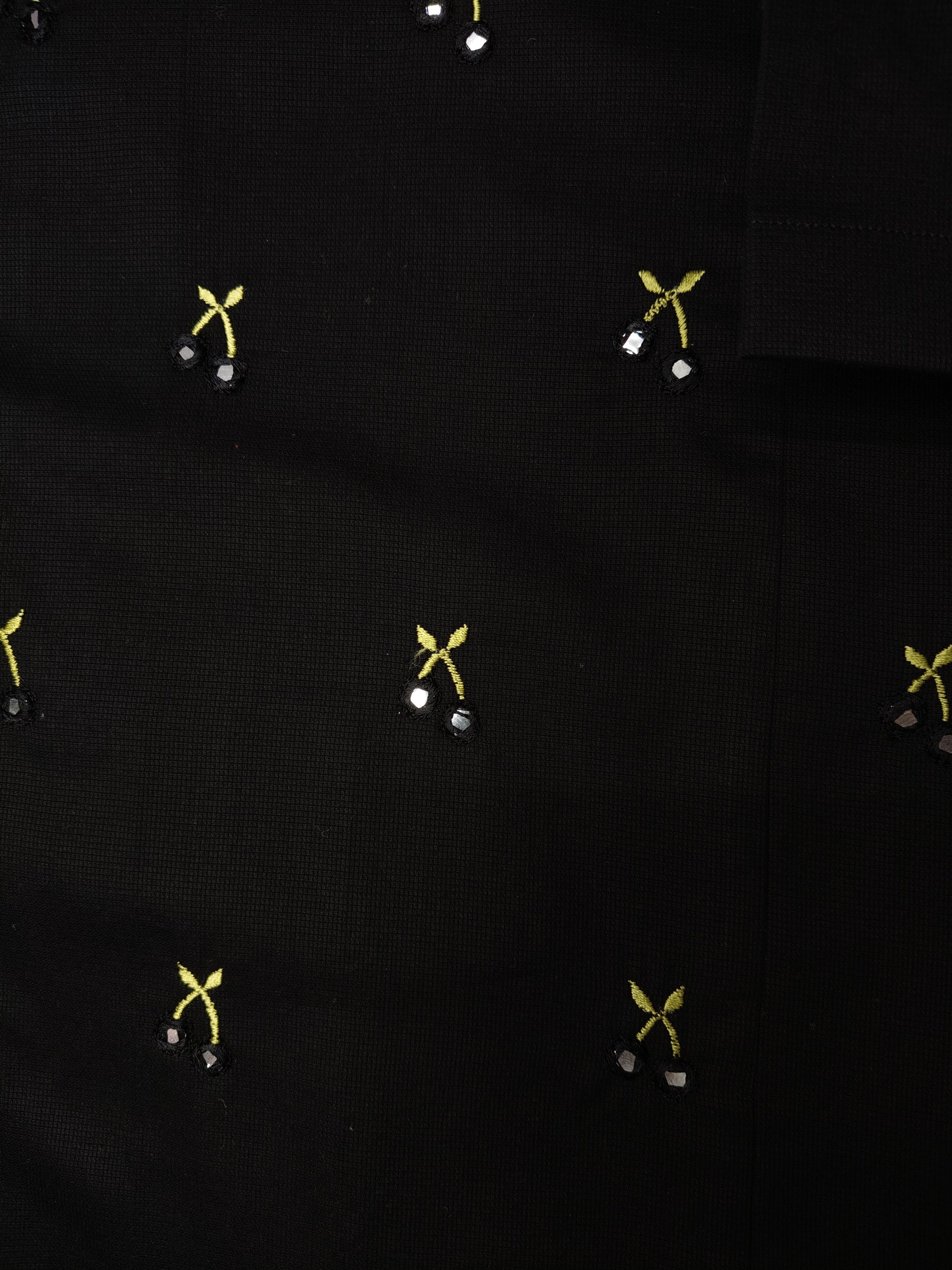 Close-up of the embroidery detail of the shirt featuring hand-done mirror work to resemble cherries