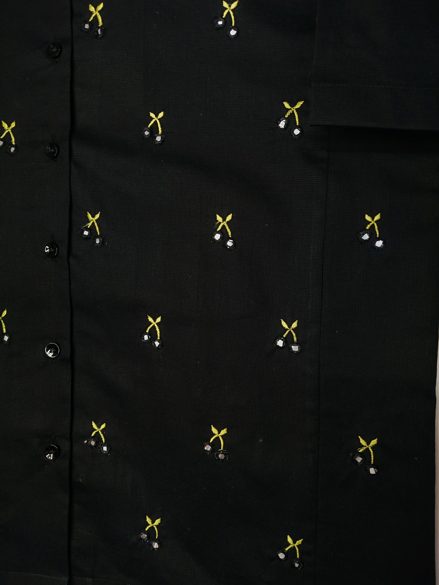 Close-up of the embroidery detail of the shirt featuring hand-done mirror work to resemble cherries